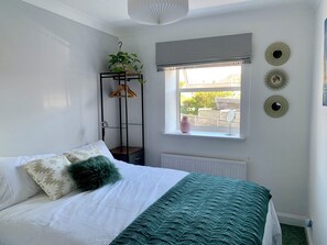 A bedroom with a bed, a window with a view, a plant, and wall decorations.