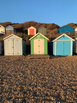 A row of beach huts numbered 403, 404, and 405, with a gravel path in front.