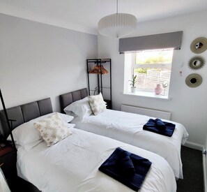 Een hotelkamer met twee bedden, een raam met uitzicht en een plafondlamp.