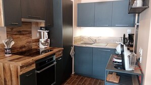 A modern kitchen with dark cabinets, a wooden countertop, and a built-in oven. - Cozy Apartment in Châtel, 6 Pers. (Châtel)