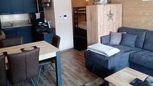A modern living room with a sofa, a dining table, and a kitchen area. - Cozy Apartment in Châtel, 6 Pers. (Châtel)