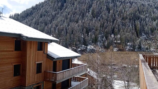 A wooden building with a balcony, surrounded by snow-covered trees and a mountain in the background. - Cozy Apartment in Châtel, 6 Pers. (Châtel)
