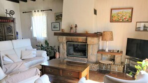 Un salon chaleureux avec un canapé blanc, une cheminée, un téléviseur et divers objets décoratifs.