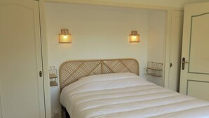 Une chambre à coucher avec un lit, deux lampes fixées au mur et une porte.