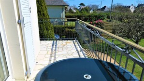 Une piscine extérieure de forme circulaire, entourée d’une balustrade en métal, d’une terrasse en pierre et d’un jardin agrémenté de diverses plantes et fleurs.