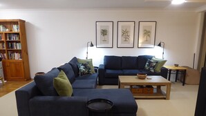 A living room with a dark blue sofa, a smaller sofa, a coffee table, and a bookshelf. - Braemar Unit 3 (Forster)
