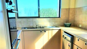 A compact kitchen with a window, a built-in oven, a sink, and a dishwasher. - Braemar Unit 3 (Forster)