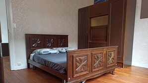 Ein Bett mit hölzernem Kopfteil und Fußteil, ein Kleiderschrank und eine Tür mit Spiegel.