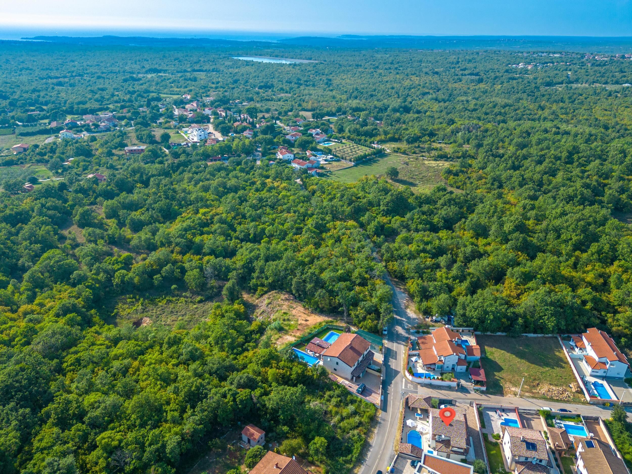 Vista aérea de una zona residencial con casas, carreteras y una extensa área boscosa.
