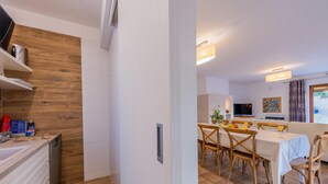 A modern kitchen with wooden accents, a dining area with wooden chairs and a table, and a living area with a sofa and TV. - Villa Artist near Porec (Poreč)
