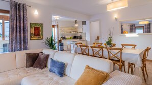 A modern living room with a sofa, dining table, and chairs. There is a kitchen in the background with a dining area. - Villa Artist near Porec (Poreč)