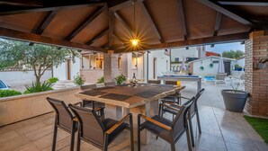 An outdoor patio with a wooden table and chairs, a pool, and a brick wall. - Villa Artist near Porec (Poreč)