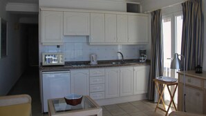 A compact kitchen with white cabinets, a microwave, a coffee maker, and a small dining area with a table and chairs.