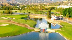 A golf course with a pond, a distinctive spherical sculpture, and a small building. - VILLA MIJAS PLAYA (AN)