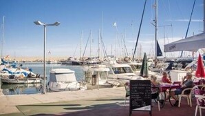A marina with boats docked, a café with outdoor seating, and a clear sky. - VILLA MIJAS PLAYA (AN)