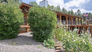 A rustic log cabin with a covered porch and an American flag. - Aspen Bear Paws | Charming Retreat with Hot Tub & Loft (Alpine)