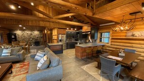 A spacious log cabin interior with a living area, kitchen, and dining space. - Aspen Bear Paws | Charming Retreat with Hot Tub & Loft (Alpine)