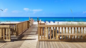 Un muelle de madera que conduce a una playa con aguas azules cristalinas y algunas personas a lo lejos.