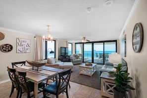 Relax in this stylish living area with a high ceiling and expansive sea views, featuring a dining table, sofa, and TV.