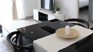 A modern hotel room with a dining area, a TV, a small plant, and a bed with a view.