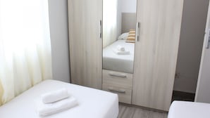 A hotel room with a bed, a wardrobe, and a small table with a towel.