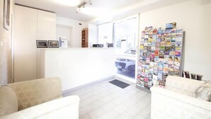 A reception area with a white counter, a wall of travel brochures, and two patterned sofas. - Manly Oceanside (Sydney)