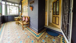 A room with a patterned floor, a bench with cushions, a wall-mounted plant, and a door with a sign reading "DURAL". - Manly Oceanside (Sydney)