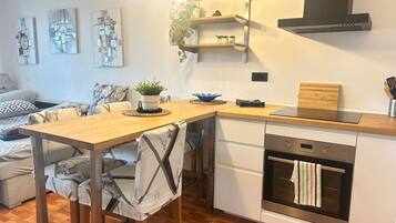 A modern kitchen with a wooden table, built-in oven, and pendant lights.