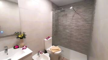 A modern bathroom with a sink, bidet, and a shower area.