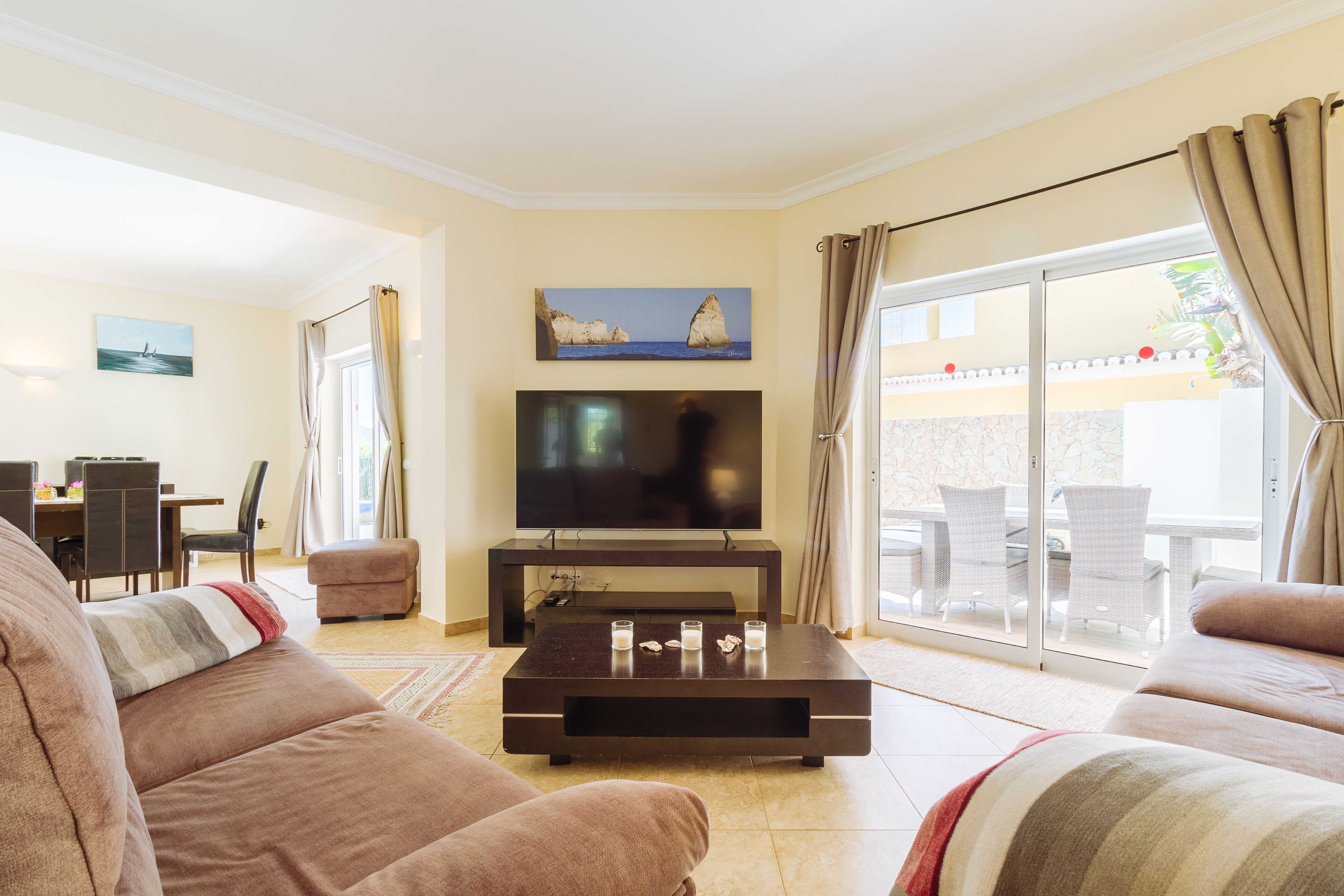 Ein Wohnzimmer mit Flachbildfernseher, einer Couch, einem Couchtisch und einem Essbereich mit Stühlen und Tisch.