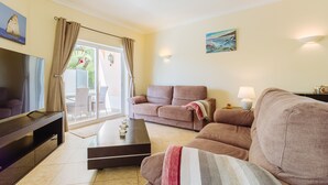 A living room with a sofa, a coffee table, a TV, and a lamp. - Poolvilla Casa Vista Mar (Carvoeiro)