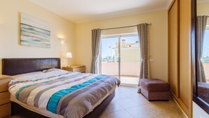 A hotel room with a bed, a nightstand, a lamp, a window with curtains, and a balcony. - Poolvilla Casa Vista Mar (Carvoeiro)