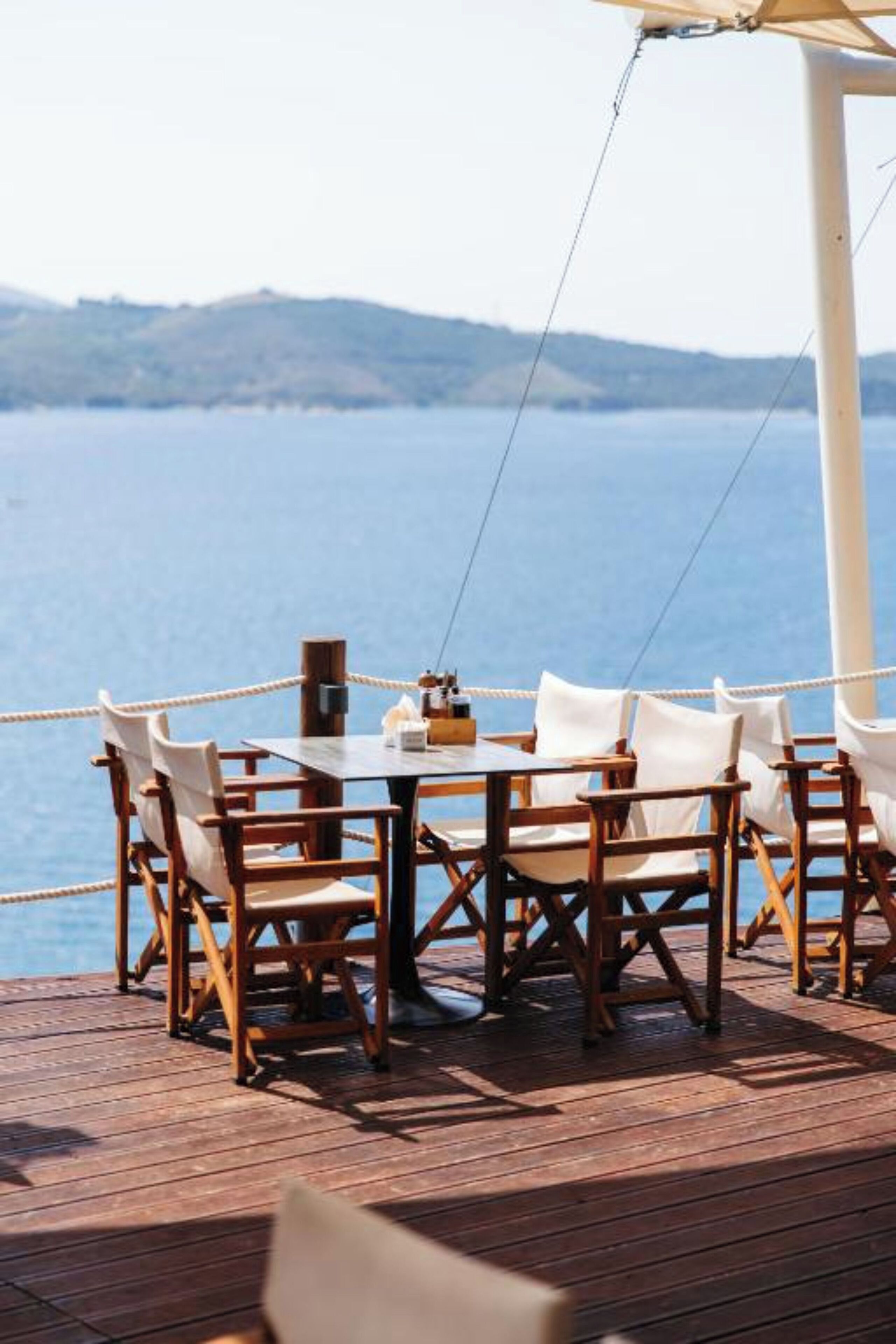 A wooden deck with a table and chairs overlooking a body of water.