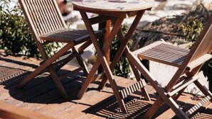 A wooden table with two chairs on a terrace overlooking the sea. - Arameras Resort (Ksamil)