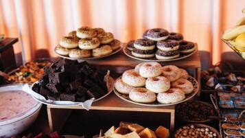 Uma mesa de buffet com diversos doces, incluindo donuts, brownies e outras sobremesas.