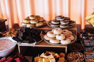 Uma mesa de buffet com diversos doces, incluindo donuts, brownies e outras sobremesas.