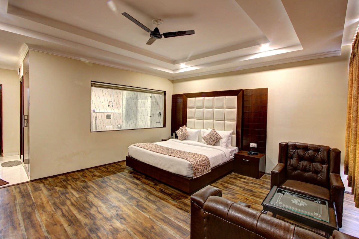 A modern bedroom with a large bed, a sitting area, and a ceiling fan.