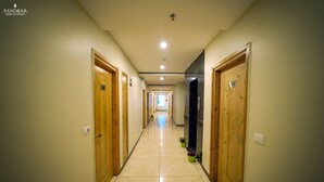 A hotel hallway with wooden doors, tiled flooring, and potted plants. - Regenta Place Green Leaf Manali- A Centrally Heated Resort (Manali)