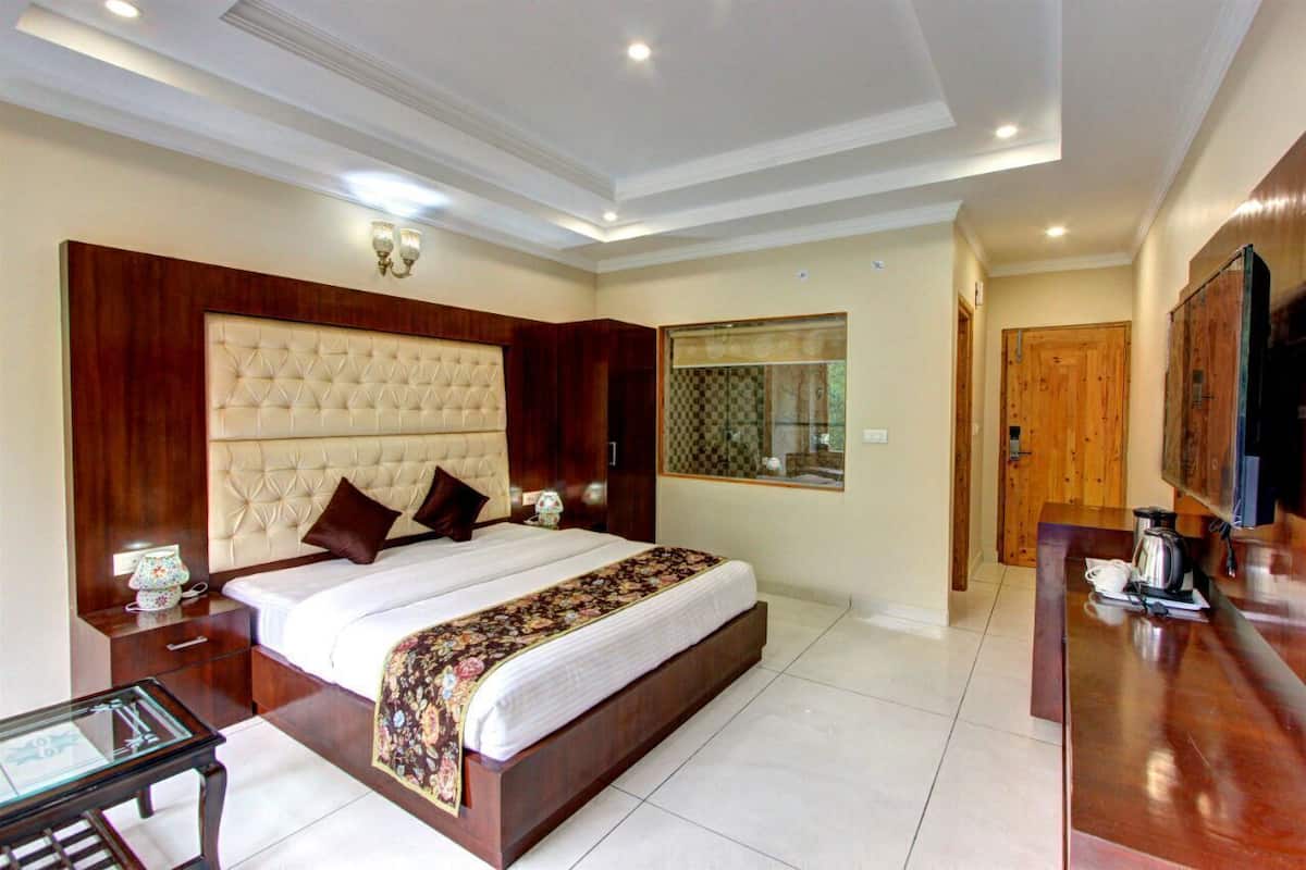A spacious bedroom with a large bed, wooden headboard, bedside tables, and a television.