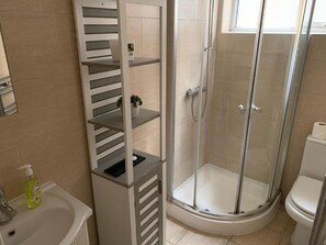 A bathroom with a glass-enclosed shower, a toilet, and a sink with a soap dispenser. - Portobello Stays by Stay Guru (London)