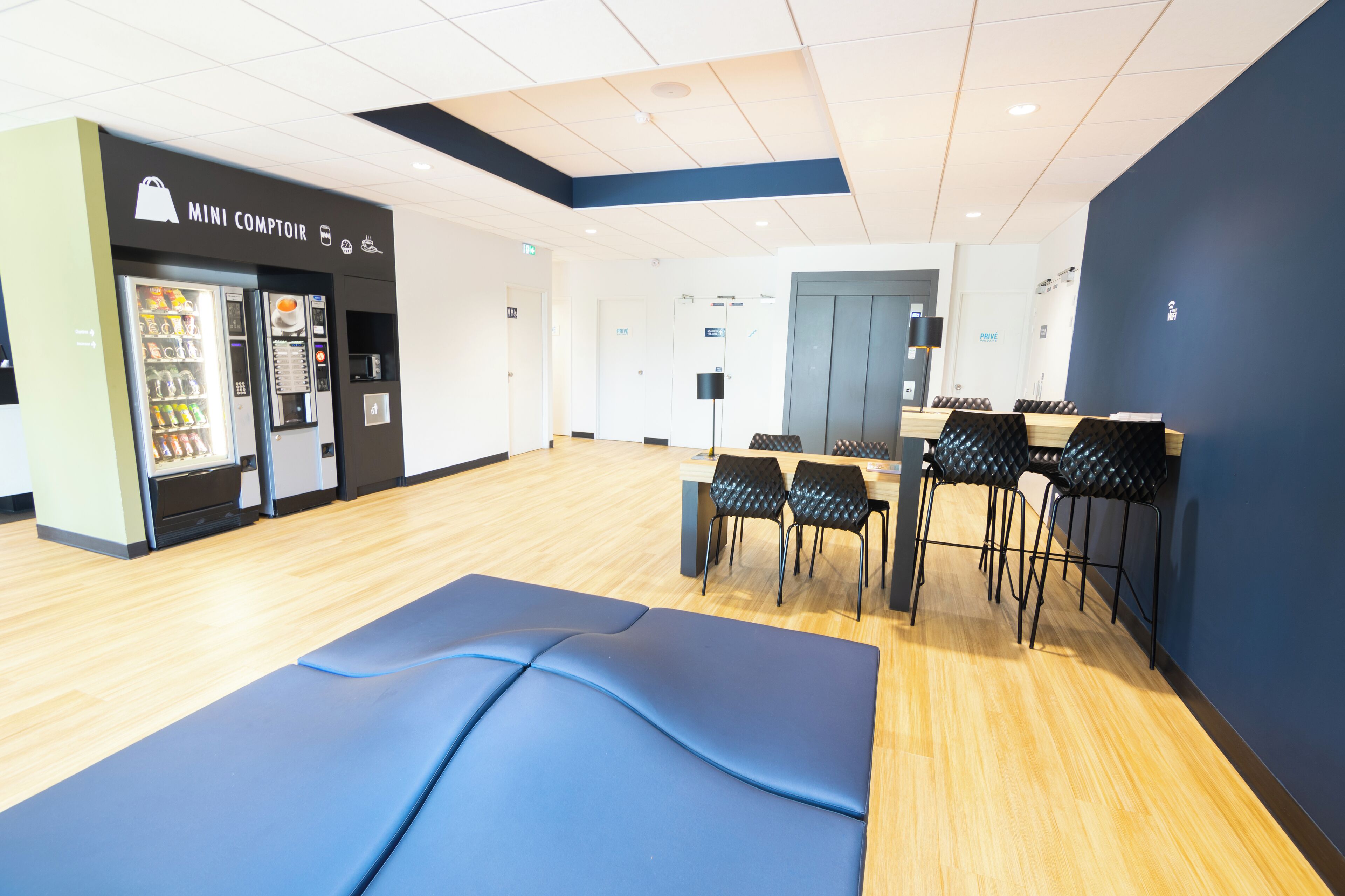 A gym with a vending machine, exercise mats, and black chairs.