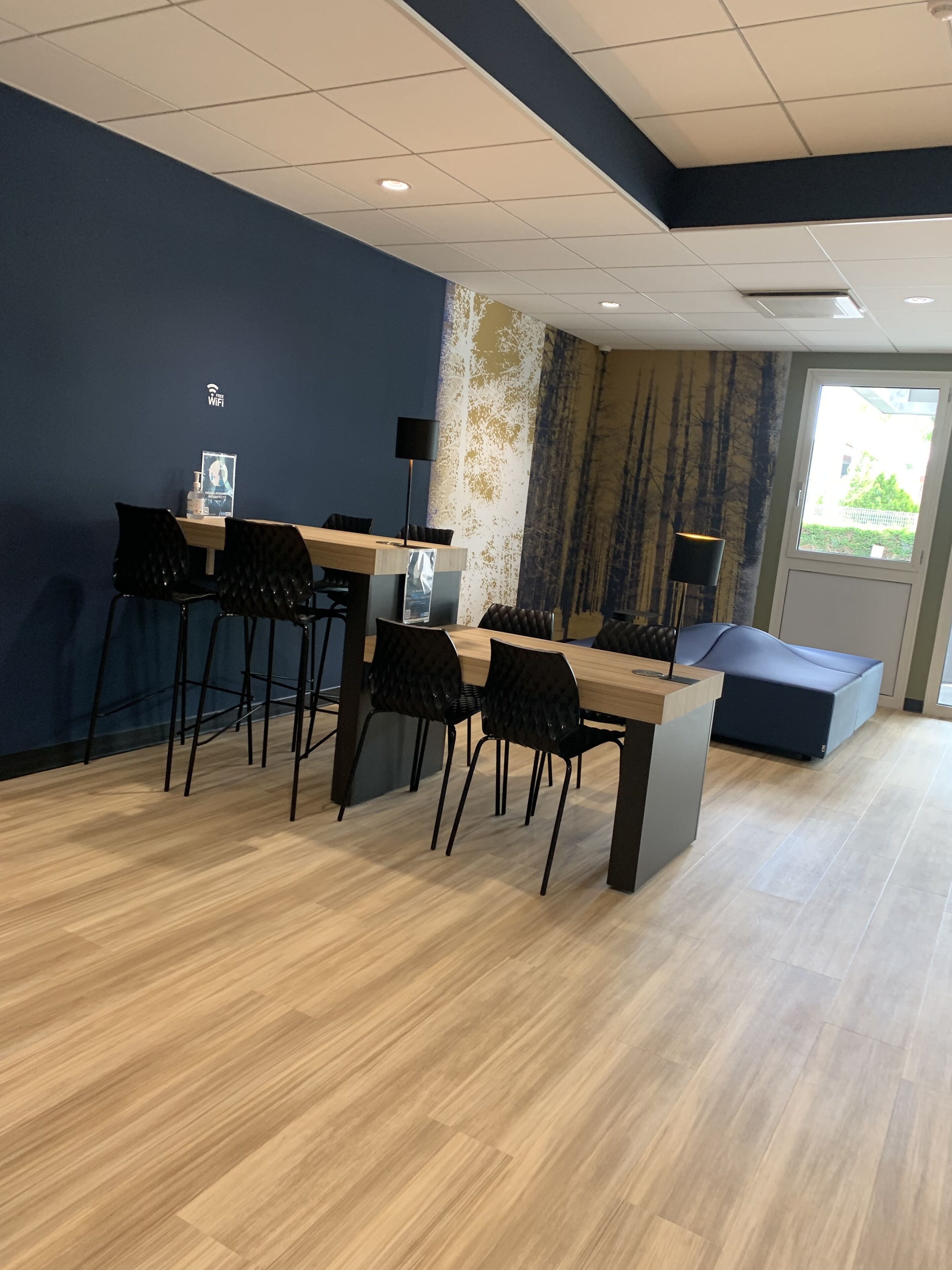 Una sala de reuniones moderna con una mesa de madera, sillas negras y una pared azul de acento.