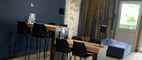 A modern meeting room with a wooden table, black chairs, and a blue accent wall.