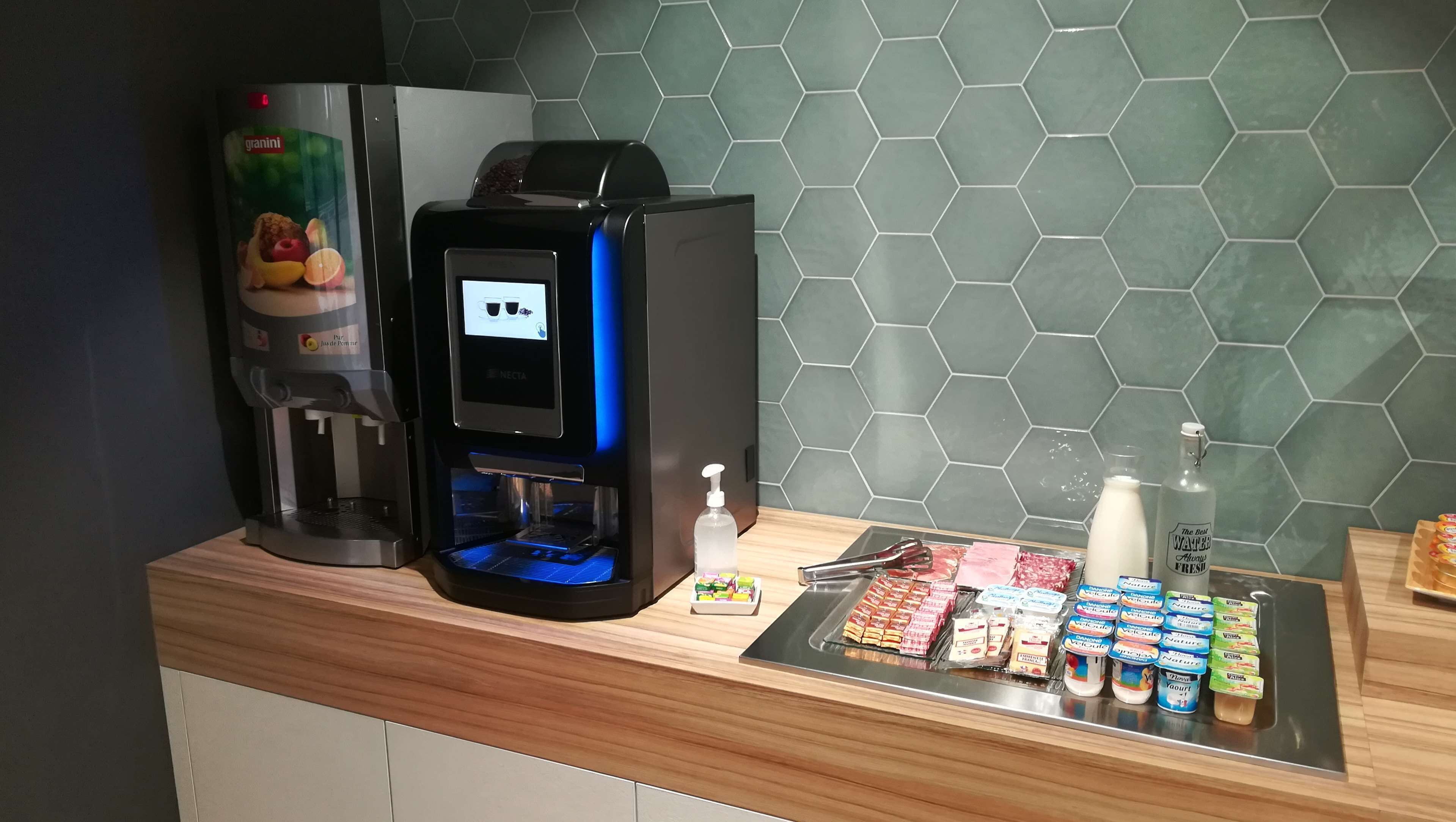 A coffee machine, a bottle of hand sanitizer, and a selection of dairy products on a counter.