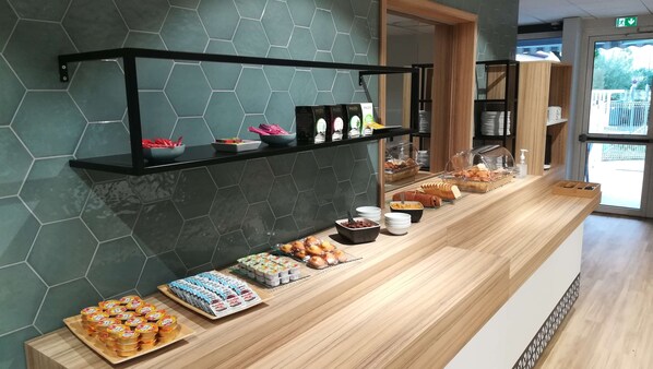 Un área de bufé con diferentes opciones de comida y una estantería con productos envasados.