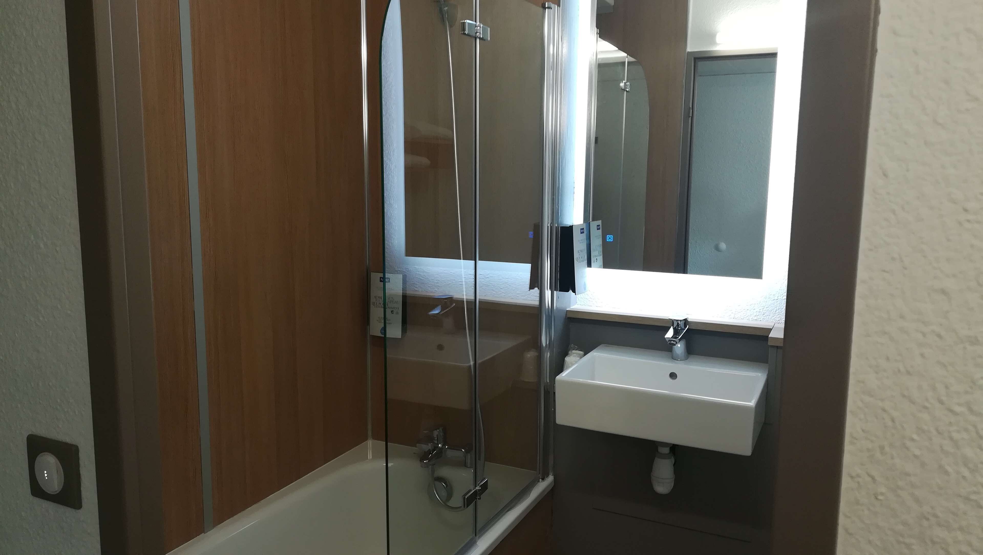 A bathroom with a glass-enclosed shower, a white sink, and a mirror above the sink.