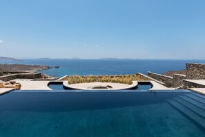 Una piscina infinita con vistas al mar y montañas lejanas.