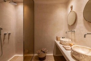 A bathroom with a shower, two sinks, a mirror, and towels.