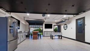 A modern kitchen with stainless steel appliances, a wooden island, and a foosball table. - 5BR House by Lambeau with Game Garage (Green Bay)