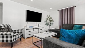 A modern living room with a flat-screen TV, a coffee table, a sofa, and a chair. - 5BR House by Lambeau with Game Garage (Green Bay)
